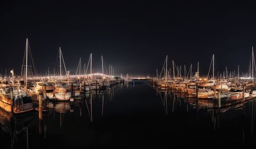 Sailboats moored in harbor at night