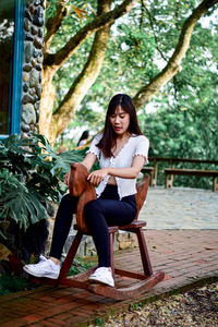 Full length of woman sitting on rocking chair outdoors