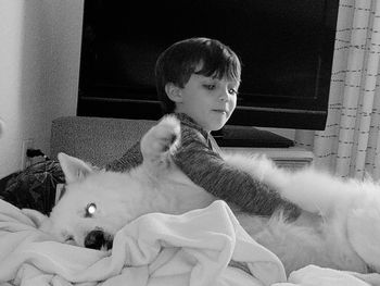 Cute boy playing with dog at home