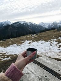 Hand holding tea cup on snowcapped mountain