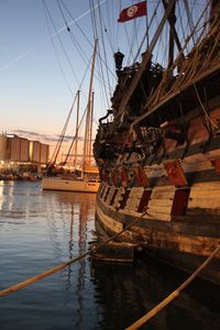 Historical boats moored at harbor against sky