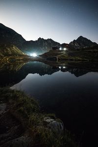Scenic view of calm lake and mountain against sky at night