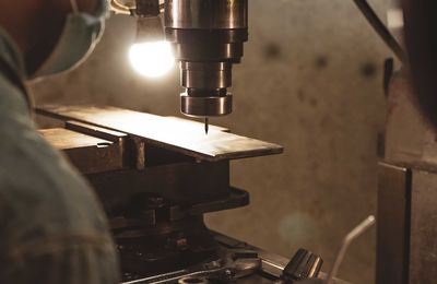 Milling machine working near worker with a protective mask. tool for cut metal workpiece. 