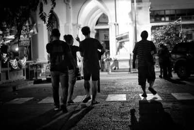 Rear view of people walking on street at night