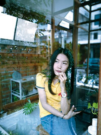 Portrait of smiling young woman looking through window