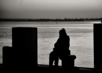 Rear view of woman standing by sea against clear sky