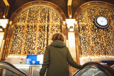 Rear view of woman walking in illuminated tunnel