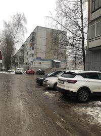 Cars on wet street by buildings in city