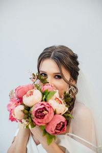 Portrait of woman holding rose against white background