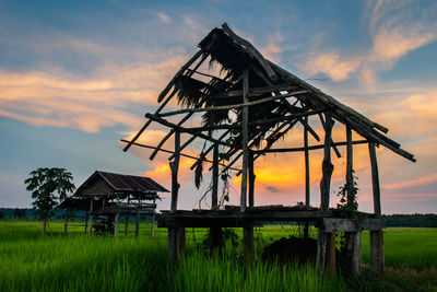 Traditional windmill on field against sky during sunset