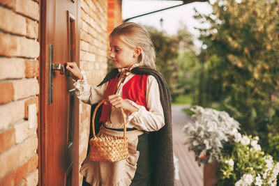 Little girl in a fairy costume with a basket in her hands is knocking on the door during