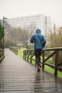 Rear view of man running on footbridge in park