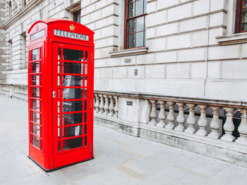 Telephone booth on sidewalk against wall