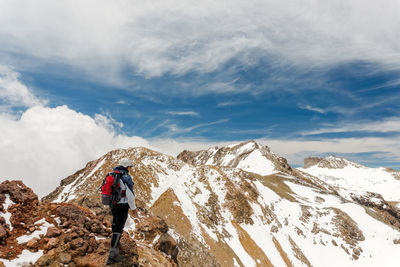 Rear view of man standing on snowcapped mountain