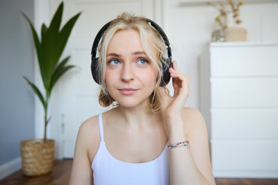 Portrait of young woman standing against wall