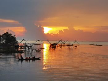 Silhouette fishing boats in sea against sky during sunset