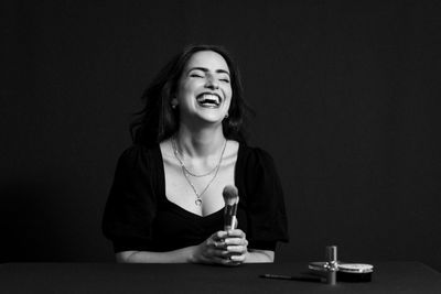 Confident woman looking at the camera and smiling while posing against a black isolated background.