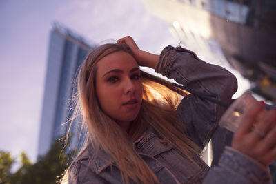 Portrait of beautiful young woman against buildings in city