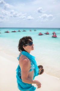 Side view of woman standing at beach against sky