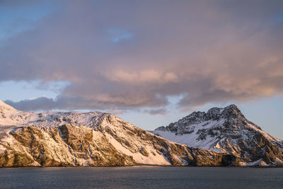 Scenic view of snowcapped mountains against sky at sunset