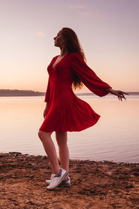 Full length of woman with umbrella against sky during sunset