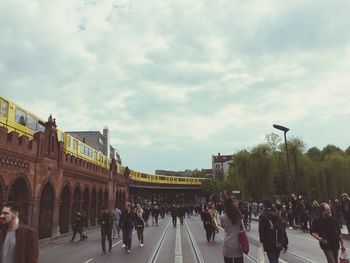 People on town square against cloudy sky