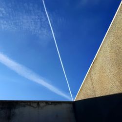 Low angle view of vapor trail against blue sky