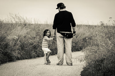 Portrait of daughter holding father hand while standing on footpath