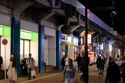 People walking on illuminated street at night