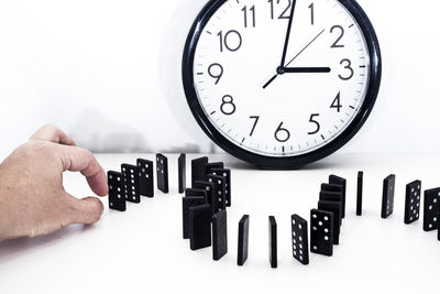 Close-up of hand holding clock against white background