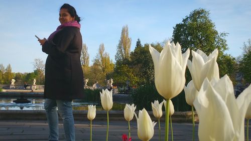 Portrait of pregnant woman standing by white tulips in park