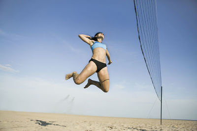 Low angle view of man jumping on beach