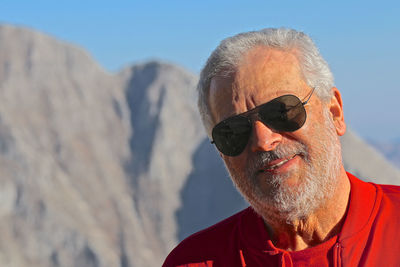 Close-up portrait of man wearing sunglasses against mountain