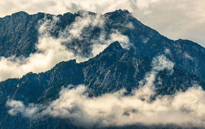 Low angle view of waterfall in mountains against sky