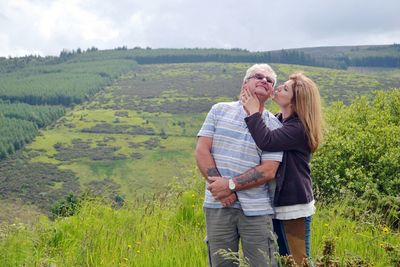 Mature woman kissing senior man while standing on field