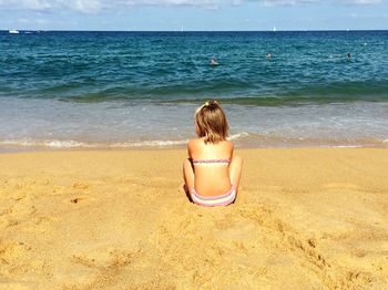 Rear view of boy on beach against sky