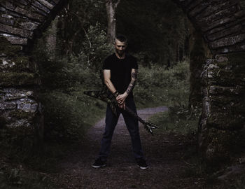 Man holding electric guitar while standing on footpath