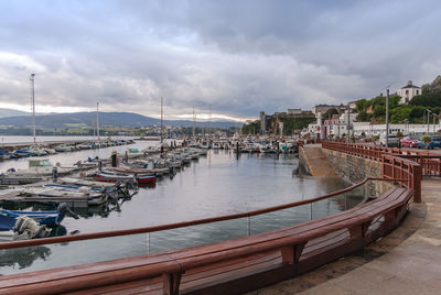 Boats moored at harbor against sky