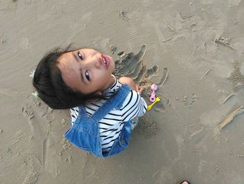 Portrait of smiling girl lying on sand at beach