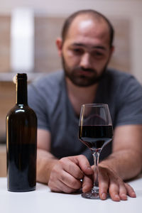 Depressed man drinking wine while sitting at home