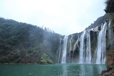 Scenic view of waterfall against sky