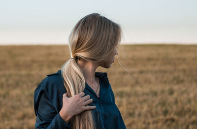 Woman looking away while standing on land against sky