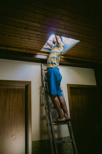 Full length of man standing on ladder at home