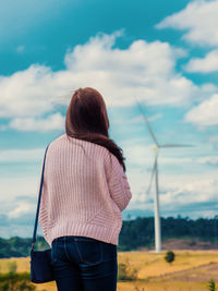 Rear view of woman standing against windmill on landscape