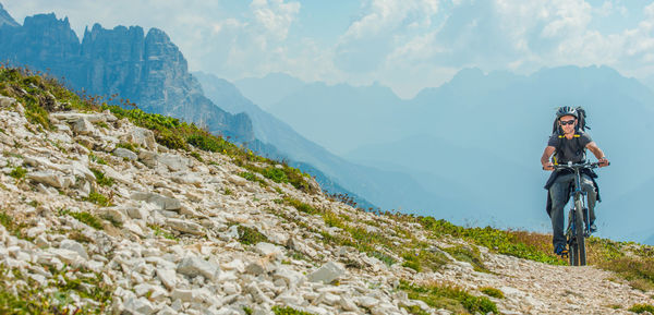 Man riding bicycle on mountain against sky