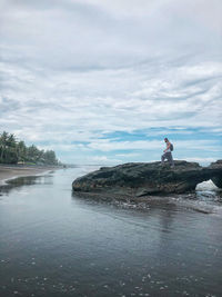 Full length of man standing on rock against sky