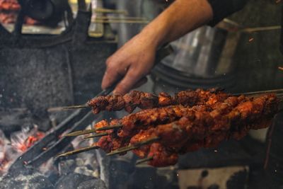 Cropped hand of man preparing meat on barbecue