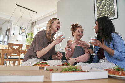 Smiling female friends eating food at home