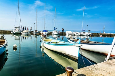 Sailboats moored in harbor