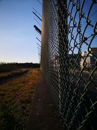 Metal fence on field against sky